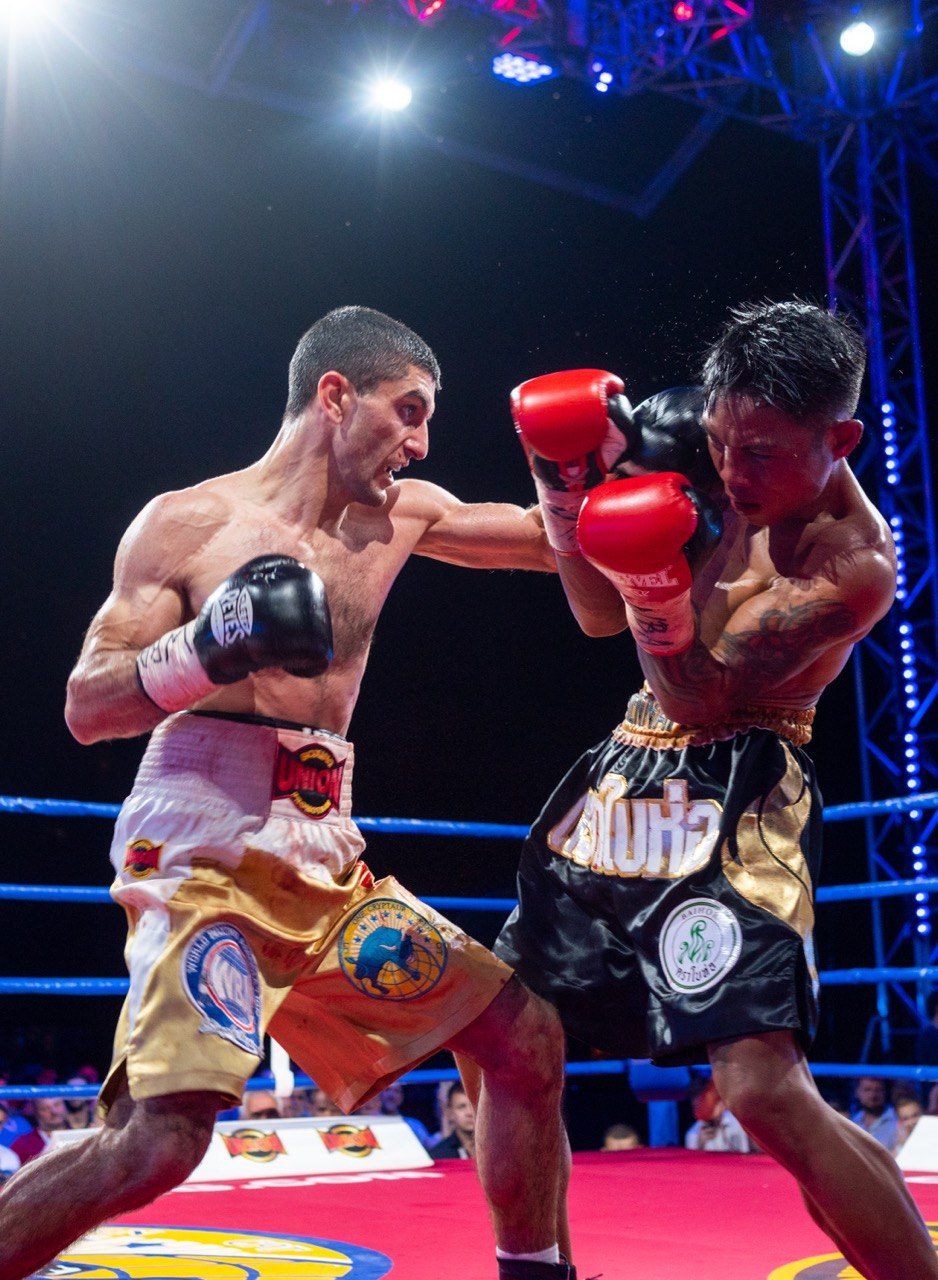 Artem Dalakian throwing a right hand at an opponent in a professional boxing ring under arena lights