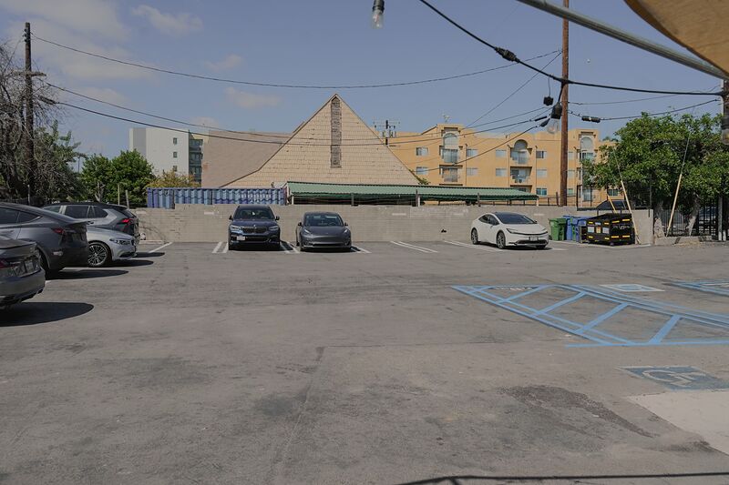 An open-air parking lot with parked cars and blue-striped accessible parking spaces